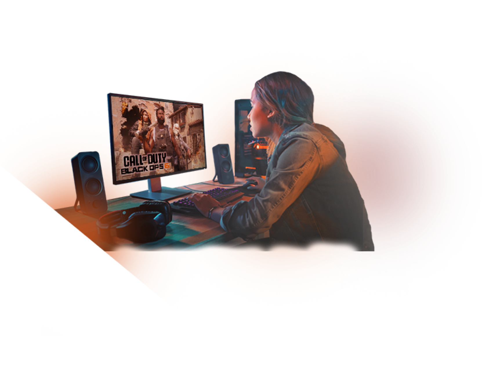A person with short hair sits at a desk playing Call of Duty: Black Ops II on a computer, surrounded by speakers, a keyboard, and headphones, with an orange glow in the background.