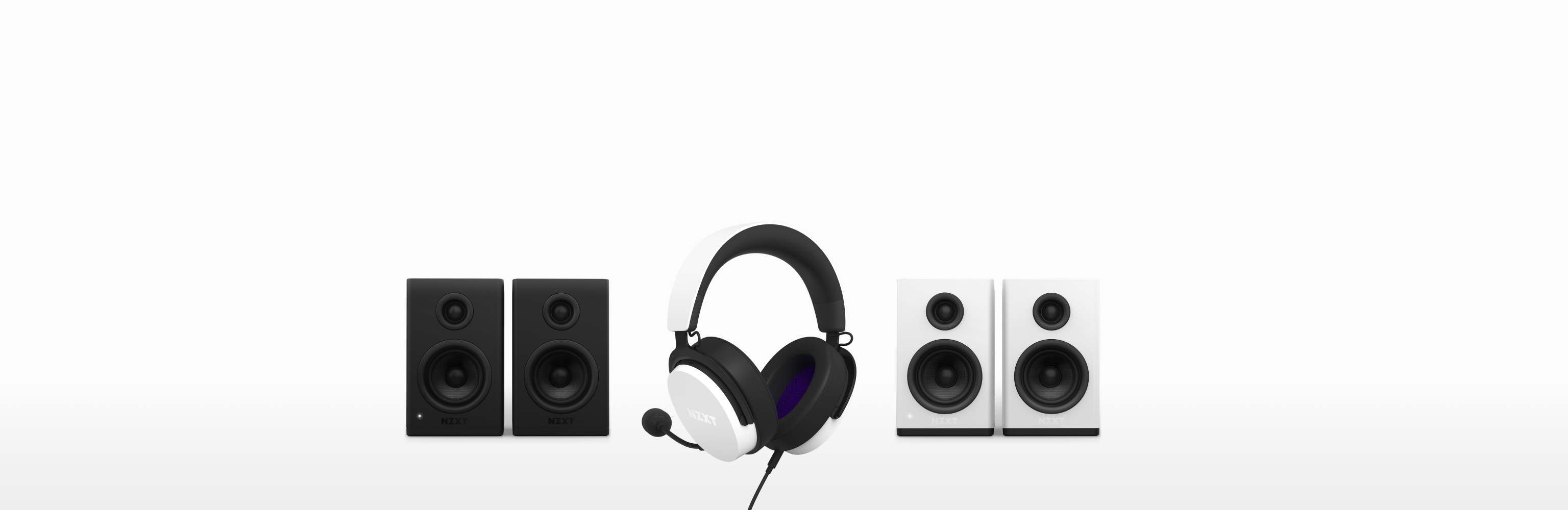 A pair of black speakers, a white and black gaming headset with a microphone, and a pair of white speakers are lined up against a white background.