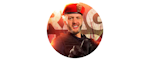 A smiling man wearing a red beret and a uniform stands in front of a background with large, partially visible text.